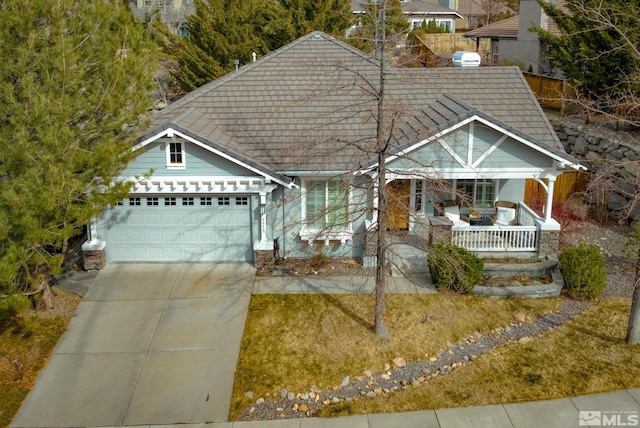 view of front of property featuring concrete driveway, a garage, and covered porch