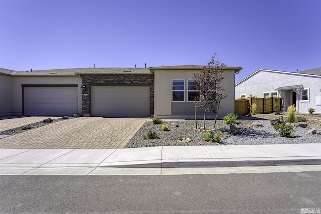 view of front facade with fence, stucco siding, decorative driveway, stone siding, and an attached garage