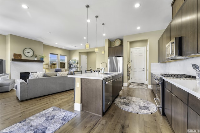 kitchen featuring dark brown cabinetry, dark wood finished floors, light countertops, appliances with stainless steel finishes, and a sink