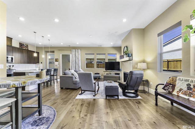 living area featuring light wood-style flooring, recessed lighting, and baseboards