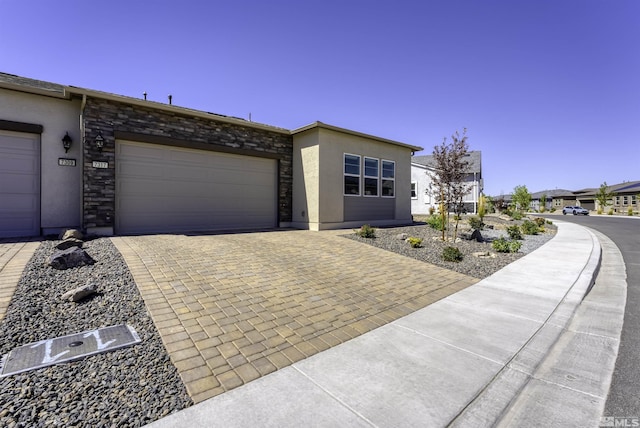 view of front of home with stone siding, stucco siding, decorative driveway, and a garage