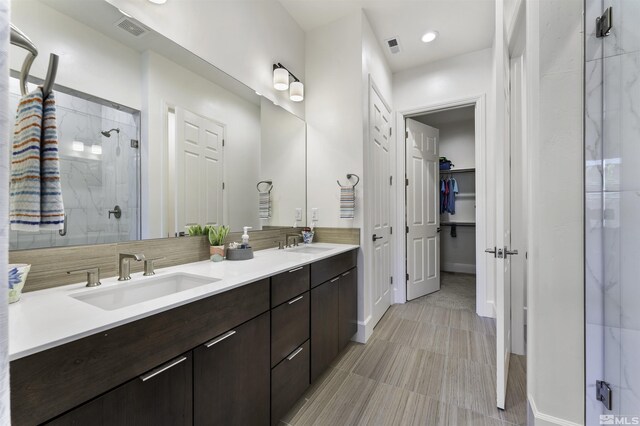 bathroom featuring a sink, visible vents, double vanity, and a shower stall