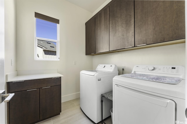 laundry room featuring baseboards, cabinet space, and washing machine and clothes dryer