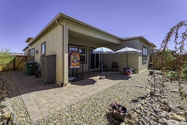 back of house featuring stucco siding, fence, and a patio area