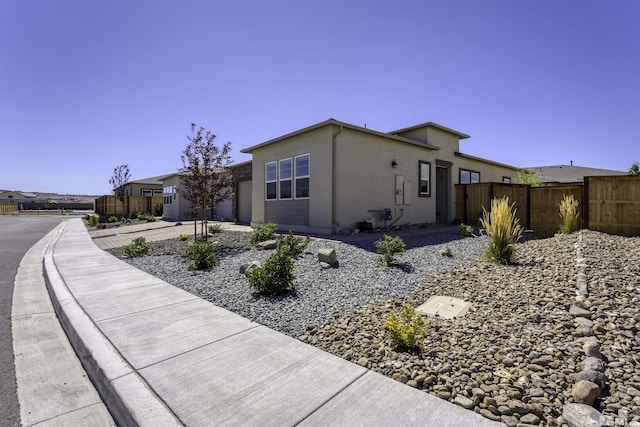 view of front of property featuring a garage, stucco siding, driveway, and fence