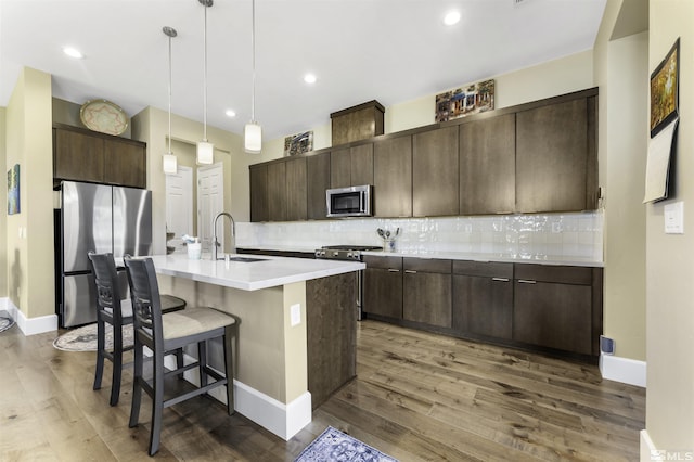kitchen with dark brown cabinetry, stainless steel appliances, tasteful backsplash, and a sink