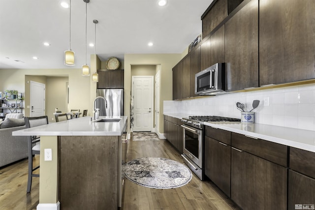 kitchen with dark brown cabinetry, open floor plan, a kitchen breakfast bar, and stainless steel appliances