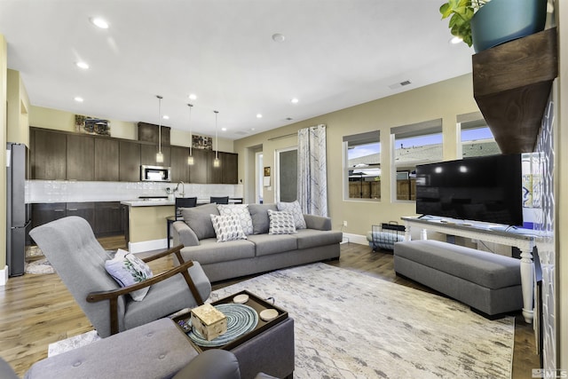 living room with light wood-style flooring, recessed lighting, visible vents, and baseboards