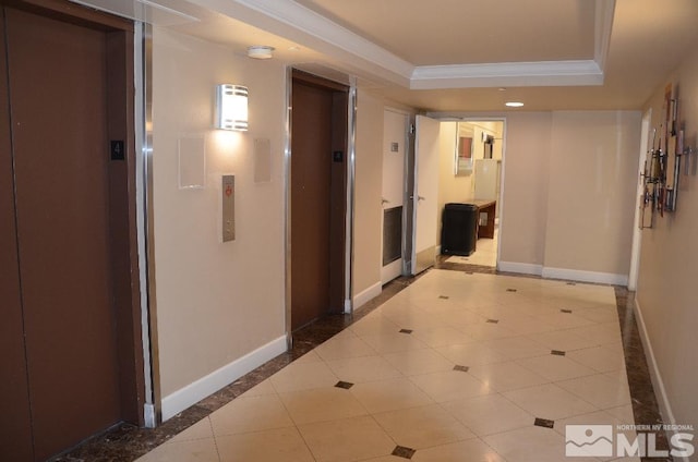 corridor featuring baseboards, elevator, tile patterned flooring, crown molding, and a raised ceiling
