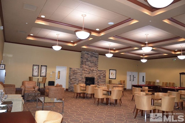 dining area featuring coffered ceiling, a stone fireplace, a towering ceiling, and crown molding