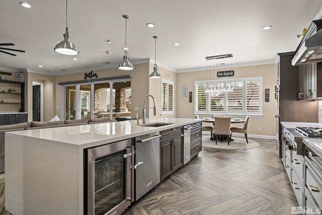 kitchen featuring open floor plan, beverage cooler, crown molding, and a sink