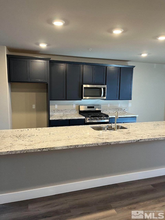 kitchen featuring a sink, recessed lighting, light stone countertops, and appliances with stainless steel finishes