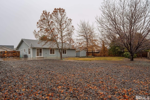view of front facade featuring an outbuilding, fence, a storage shed, central AC, and a patio area