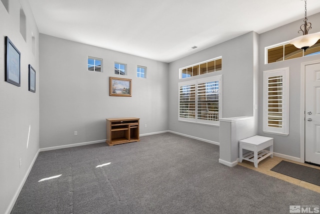 foyer featuring baseboards, carpet flooring, and visible vents