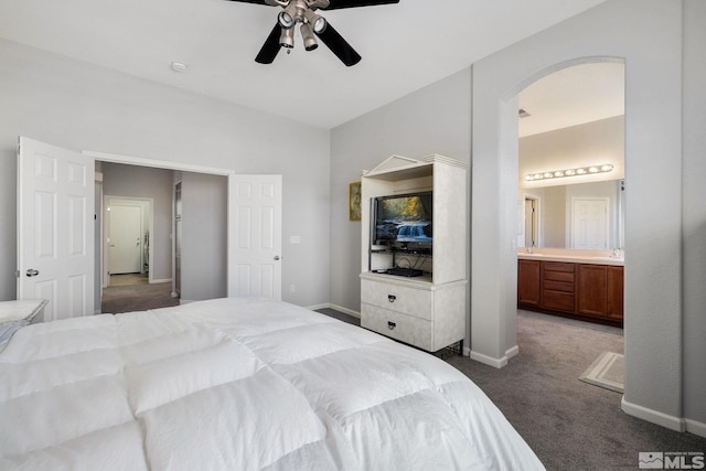 bedroom featuring connected bathroom, baseboards, arched walkways, and carpet