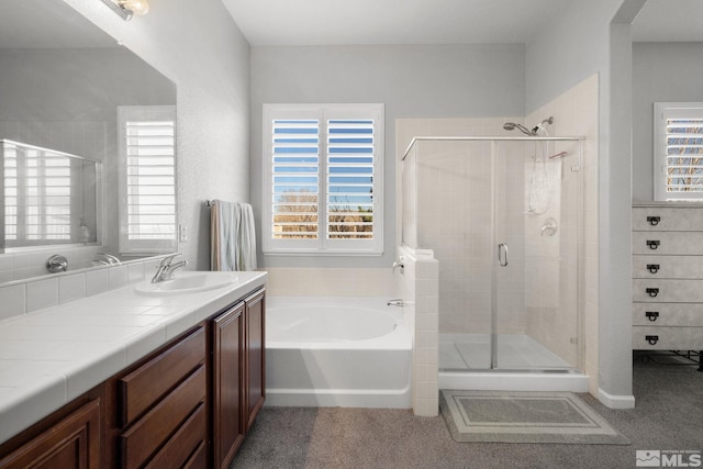 bathroom featuring a stall shower, a bath, and vanity