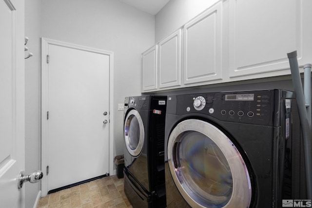 washroom with cabinet space, washing machine and dryer, and stone finish flooring
