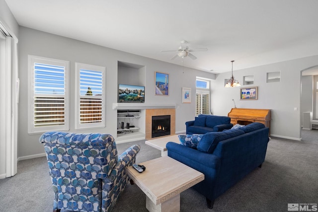 living area featuring baseboards, a tiled fireplace, ceiling fan, and carpet