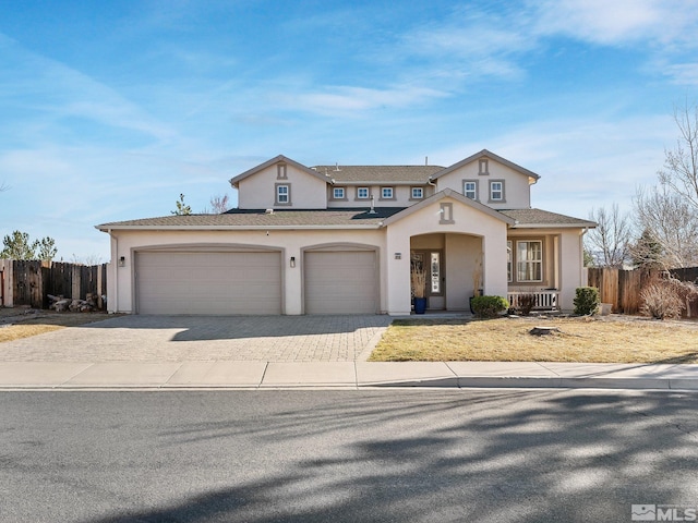 traditional-style house with decorative driveway, stucco siding, fence, and an attached garage