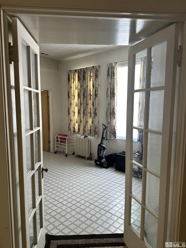 interior space featuring radiator heating unit, visible vents, french doors, and a textured ceiling