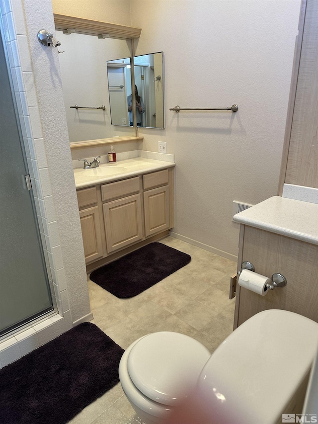 full bathroom with a stall shower, baseboards, and vanity