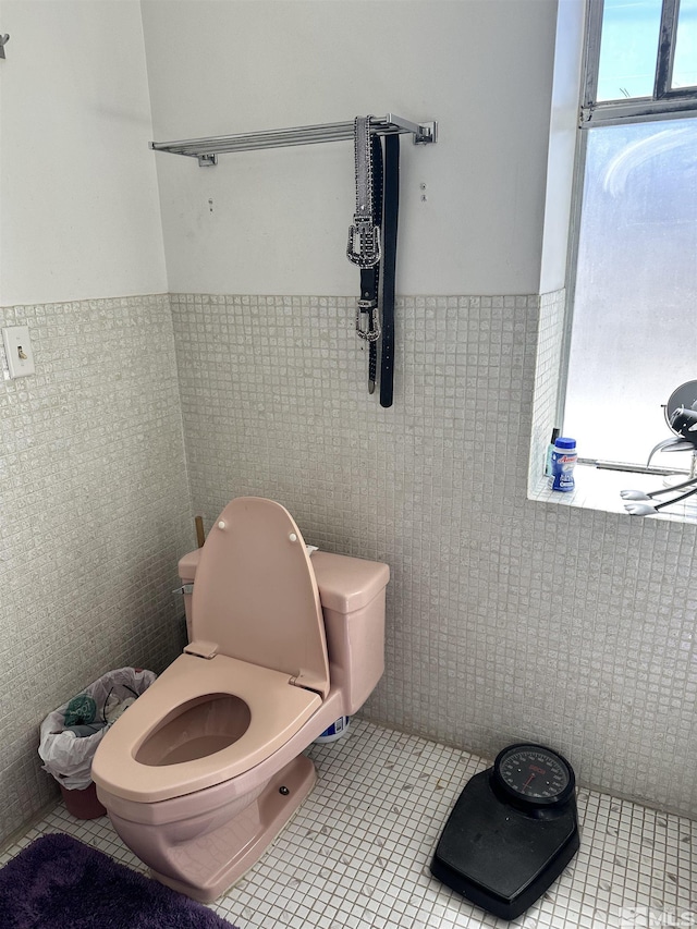bathroom with toilet, tile patterned floors, tile walls, and wainscoting