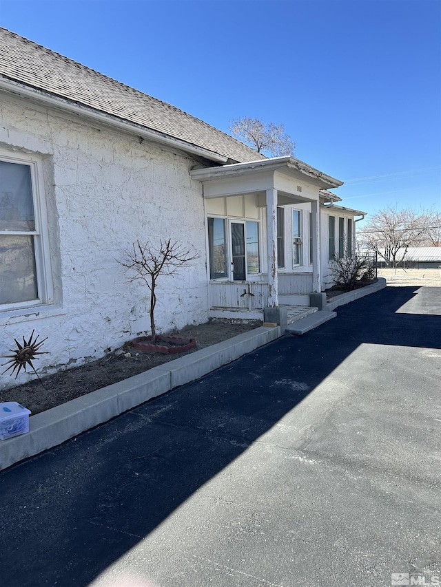 view of side of home featuring stucco siding and roof with shingles