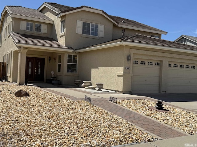 traditional home with a tiled roof, a garage, concrete driveway, and stucco siding