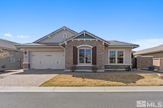 view of front of property featuring a tile roof, stucco siding, fence, decorative driveway, and a garage