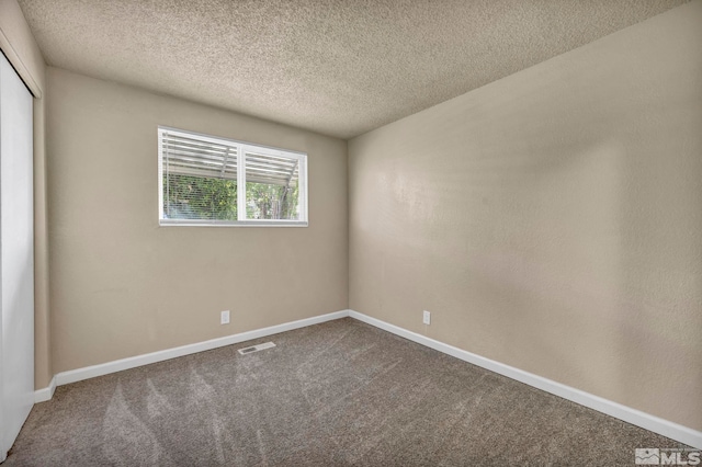 carpeted spare room featuring a textured ceiling, baseboards, and visible vents