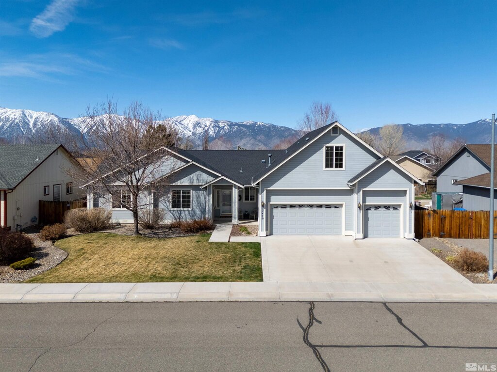 view of front of property with driveway, a mountain view, fence, and a front lawn