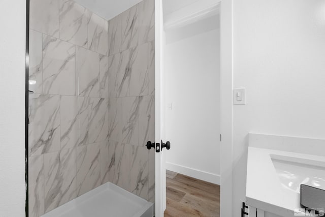 bathroom with baseboards, a marble finish shower, vanity, and wood finished floors