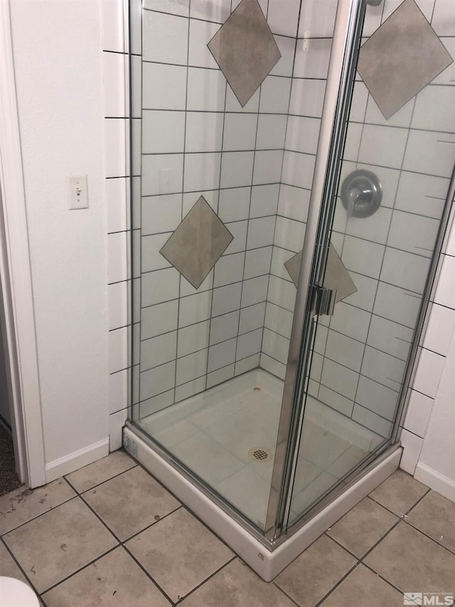 bathroom featuring a stall shower, tile patterned floors, and baseboards