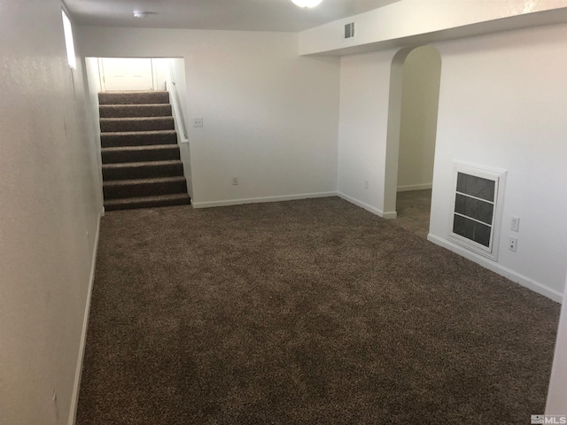 basement featuring carpet flooring, arched walkways, stairs, and visible vents