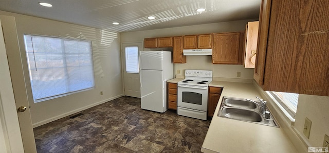 kitchen featuring light countertops, white appliances, under cabinet range hood, a sink, and brown cabinets