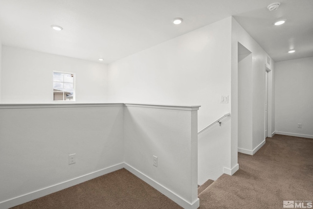 hallway featuring baseboards, carpet floors, an upstairs landing, and recessed lighting