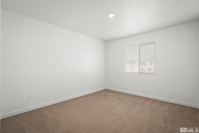 empty room featuring baseboards and light colored carpet