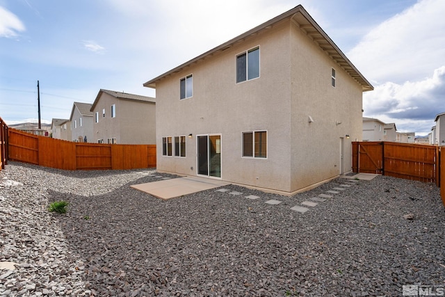 rear view of property with stucco siding, a fenced backyard, and a patio area