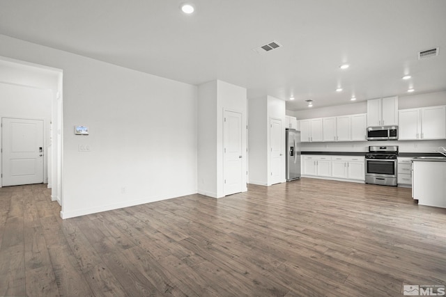 unfurnished living room featuring a sink, visible vents, recessed lighting, and wood finished floors