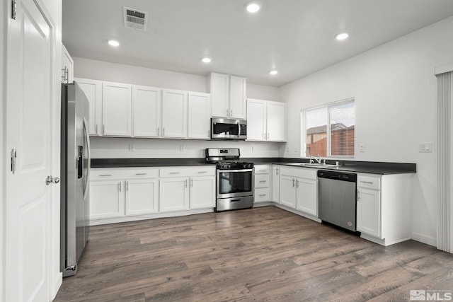 kitchen featuring visible vents, dark countertops, appliances with stainless steel finishes, dark wood-type flooring, and white cabinetry