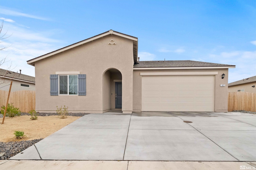 view of front facade featuring stucco siding, a garage, concrete driveway, and fence