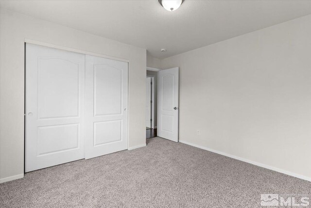 unfurnished bedroom with a closet, carpet floors, and baseboards
