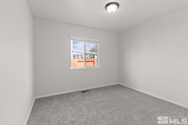 spare room with carpet flooring, baseboards, and visible vents