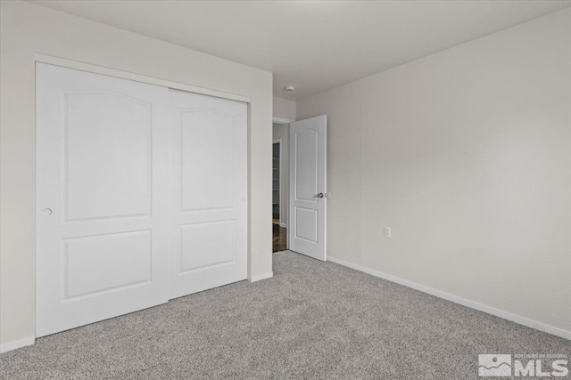 unfurnished bedroom with baseboards, a closet, and carpet