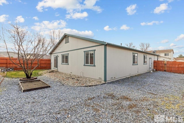 rear view of property with a fenced backyard and crawl space