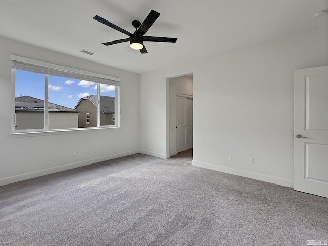 carpeted spare room featuring baseboards, visible vents, and a ceiling fan