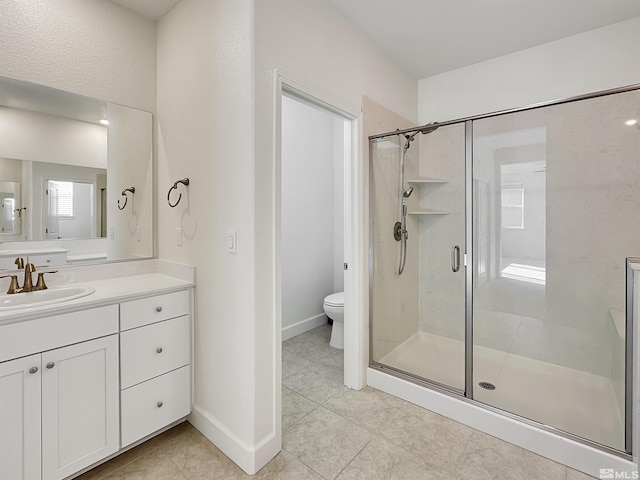 bathroom with toilet, vanity, baseboards, and a shower stall