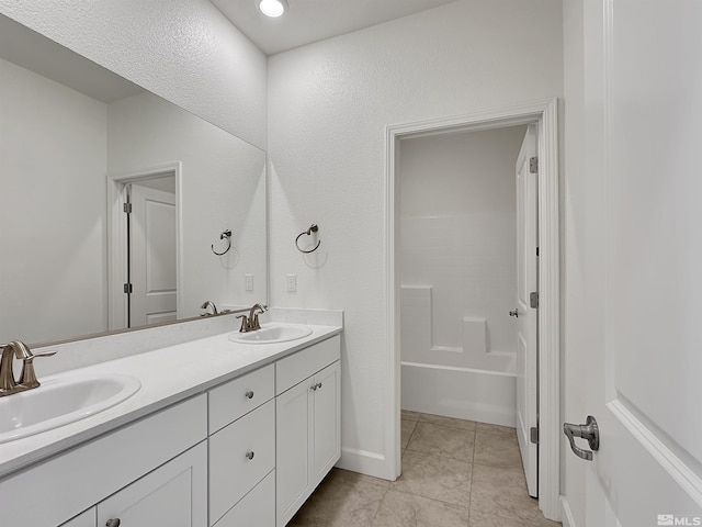 bathroom with a washtub, double vanity, tile patterned flooring, and a sink