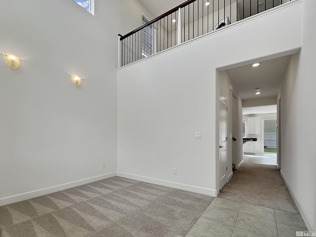 interior space featuring carpet flooring, a towering ceiling, baseboards, and recessed lighting
