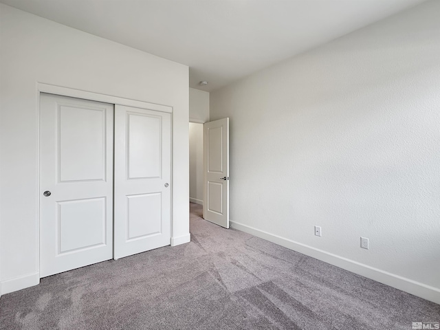 unfurnished bedroom with a closet, carpet floors, and baseboards